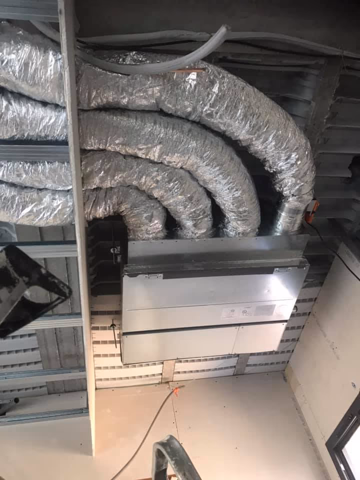 Unité intérieure de climatisation gainable en faux plafond, raccordée à des gaines souples isolées