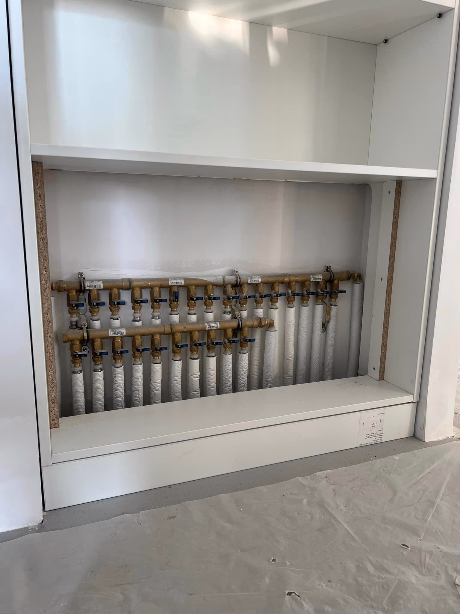 Nourrice de distribution d'eau avec collecteurs et vannes, installée dans un placard technique
