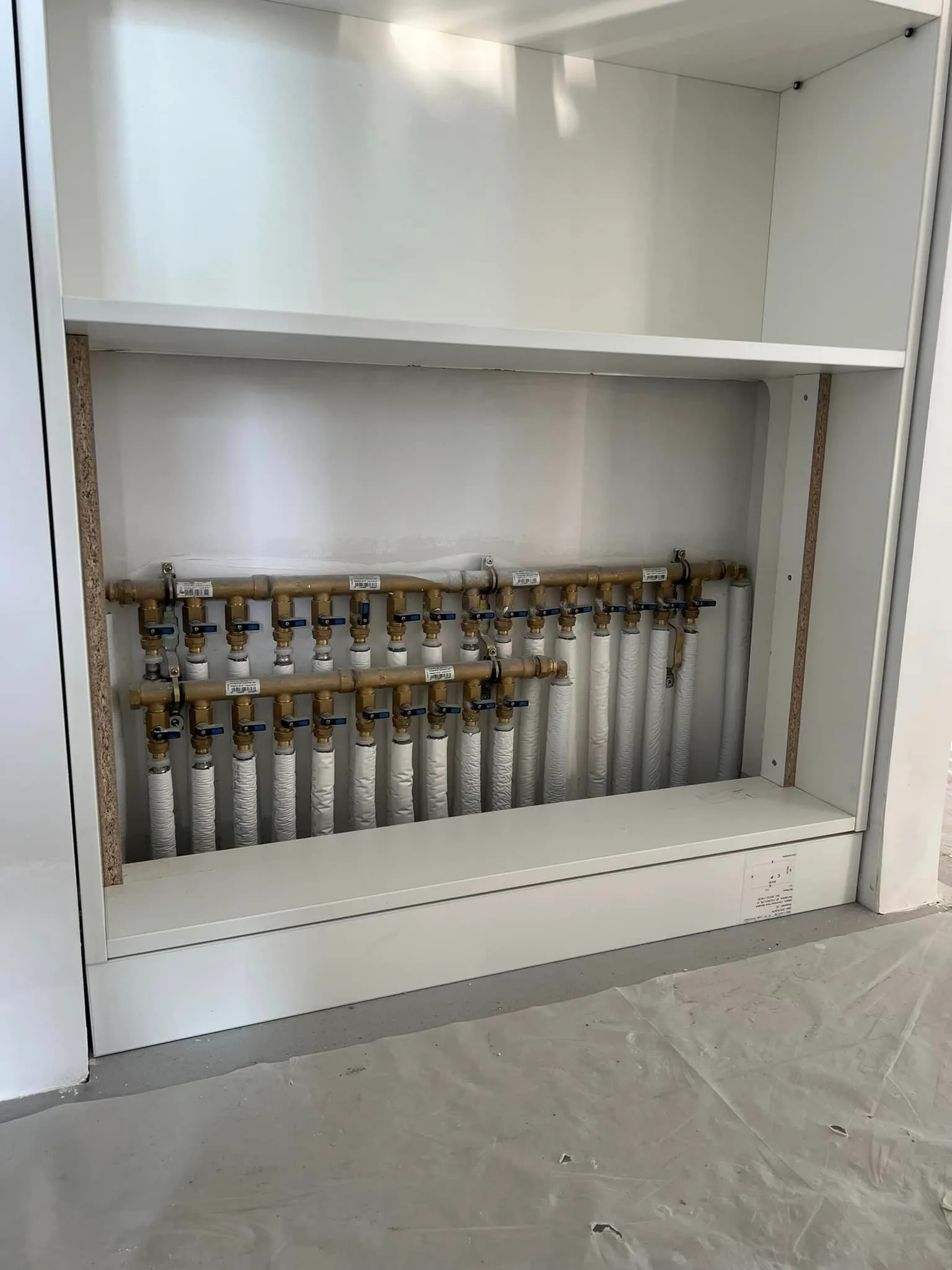 Nourrice de distribution d'eau avec collecteurs et vannes, installée dans un placard technique
